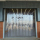 XPS Tech clear PVC strip curtain in a brick doorway — 8 in × 0.080 in × 150 ft nylon-reinforced roll