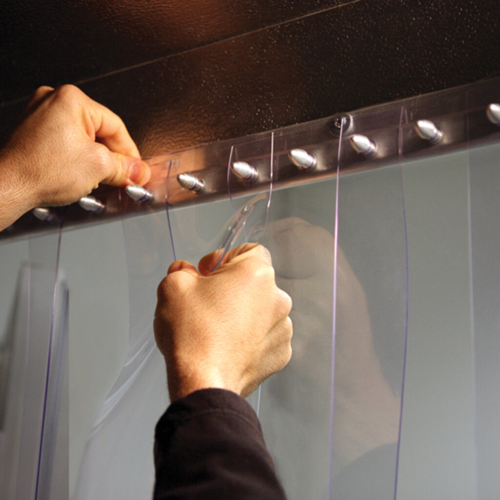 Hands installing PVC strips into an XPS Tech bullet polymer 24 in strip curtain mounting rail