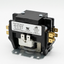A black electrical contact relay with brass and silver metal terminals, a white specification label, and a gray mounting base, photographed on a light gray background.